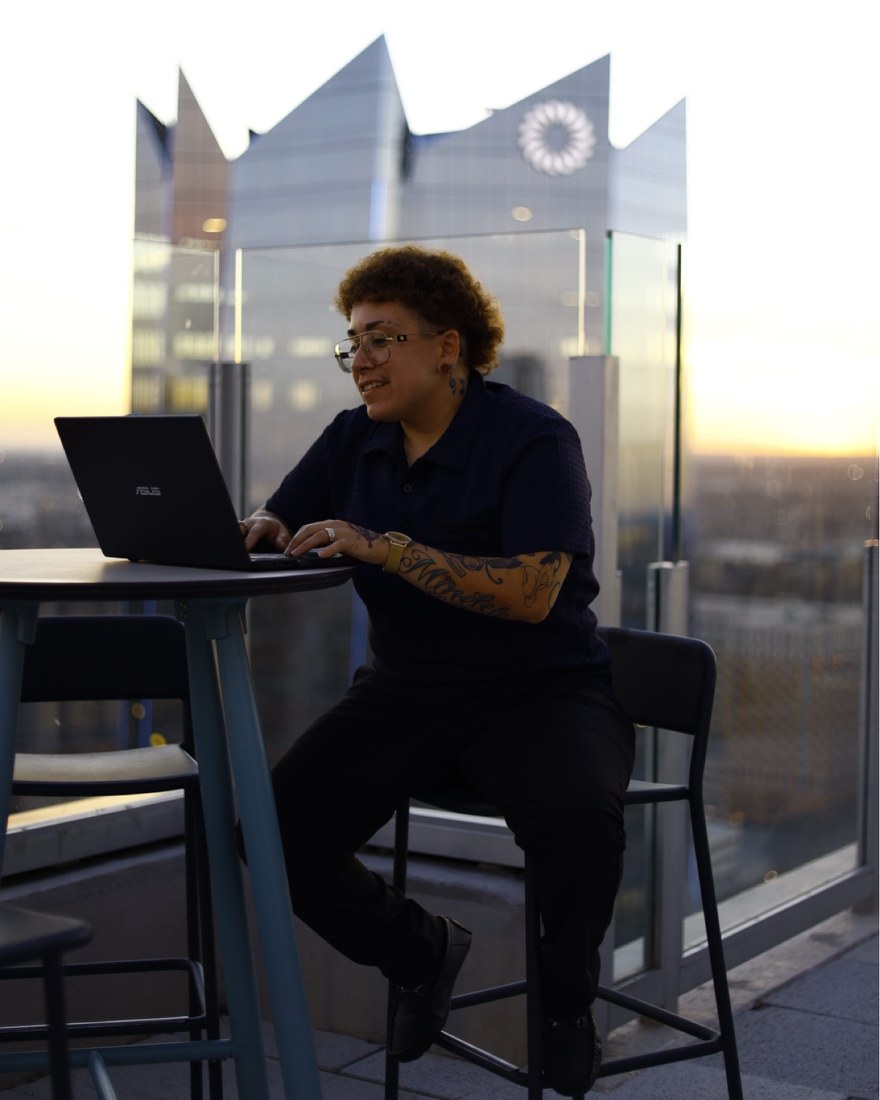Amanda Mireles working at a rooftop table at sunset.