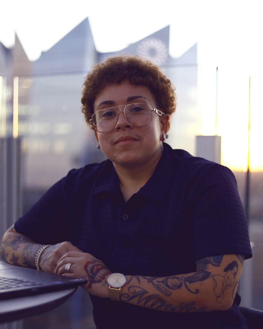 Amanda Mireles seated at a high-rise window at sunset, looking directly at the camera.